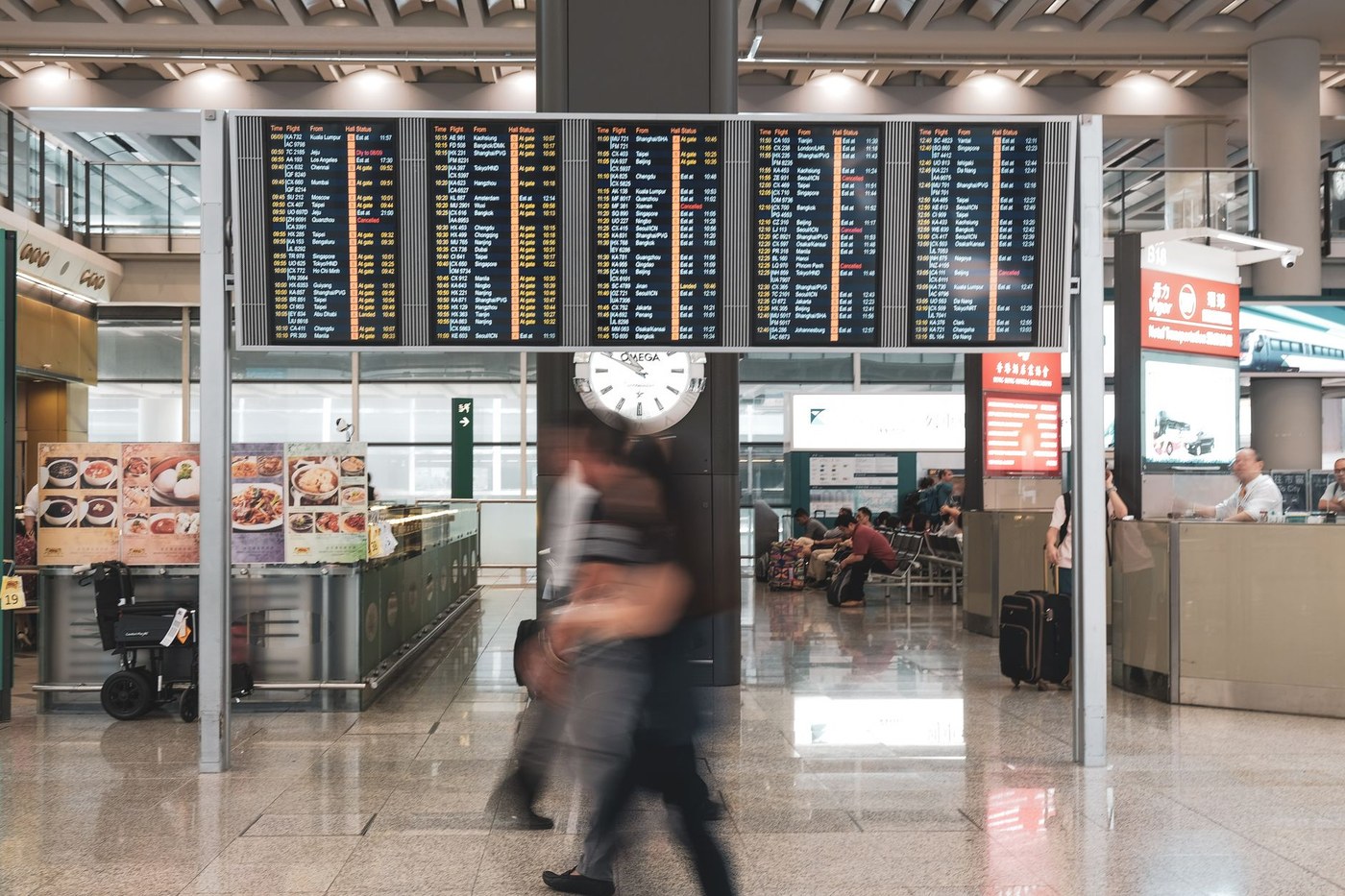 인천국제공항 출국장, 모자를 눌러쓰고 마스크를 착용한 중년 남성이 주변 취재진 질문을 피하며 빠르게 출국장으로 향하는 모습, 플래시가 터지고 긴장감 있는 분위기