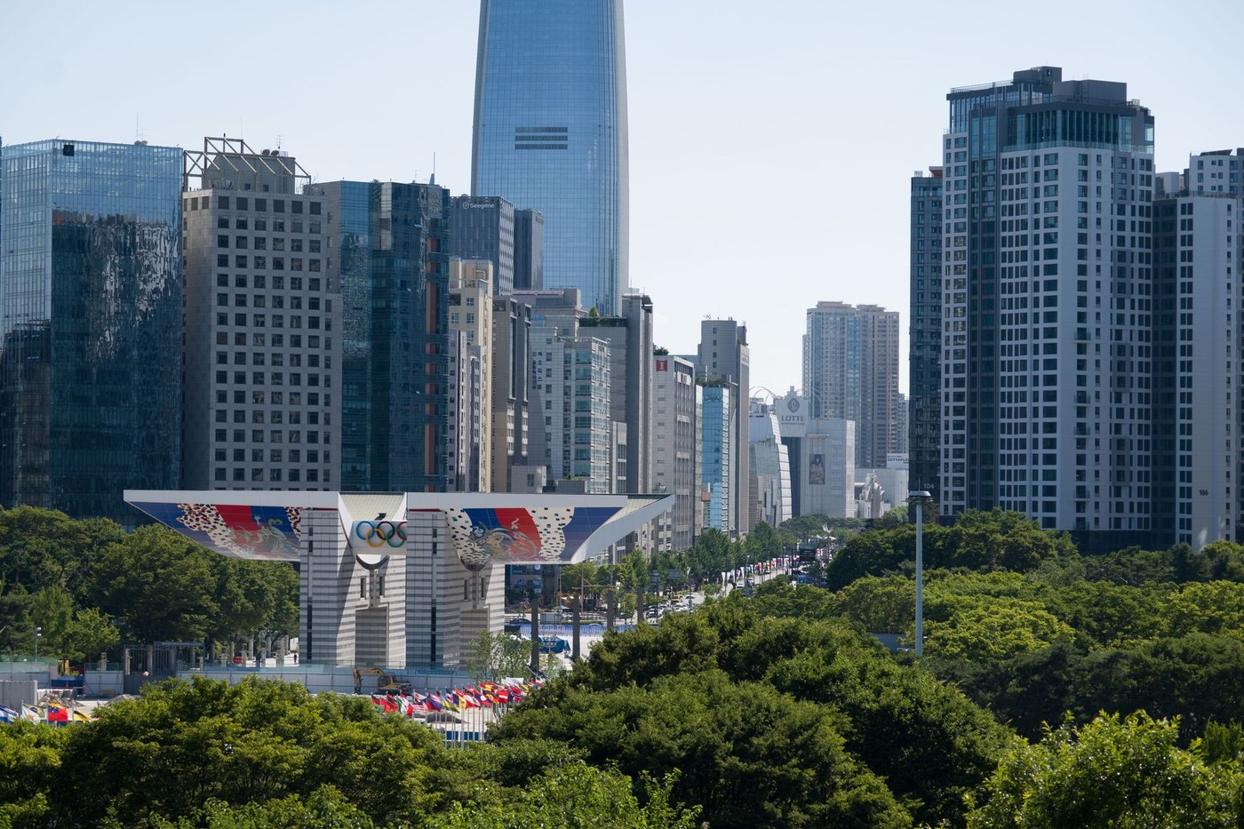 서울 도심 광장에서 태극기가 바람에 펄럭이고, 시민들이 헌법 기념 행사를 바라보는 평온한 여름 풍경