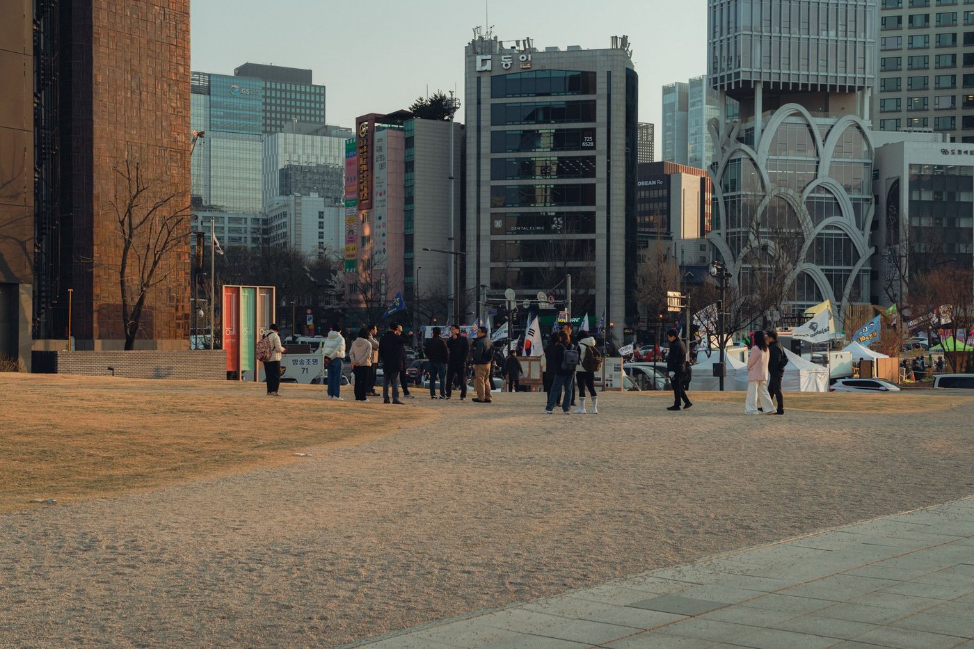야간에 서울 도심의 증권사 전광판에 sk하이닉스 주가와 그래프가 크게 표시되어 있고, 사람들 몇 명이 휴대폰으로 주가를 확인하며 서 있는 장면